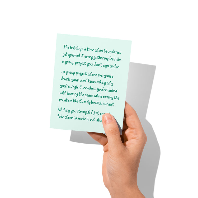 Funny holiday card held in hand, humorous holiday family message visible.