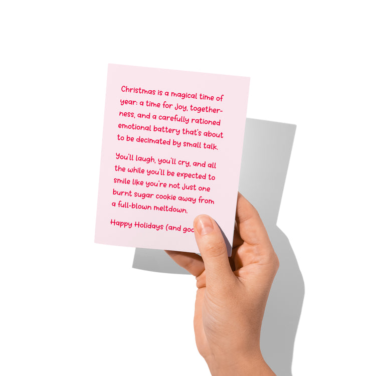 Funny holiday card held in hand, humorous Christmas meltdown design.
