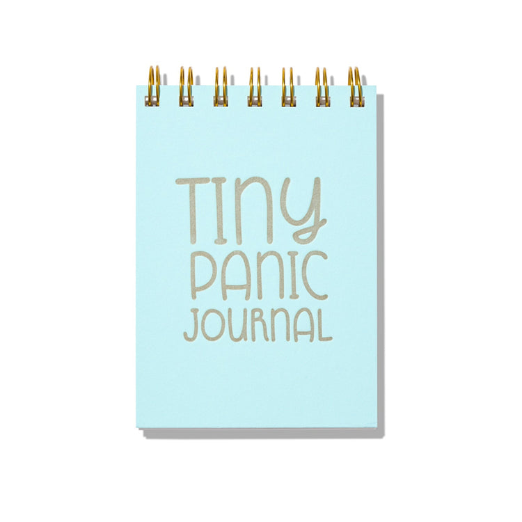 Light blue letterpress mini jotter with silver text “Tiny Panic Journal” and gold spiral binding.