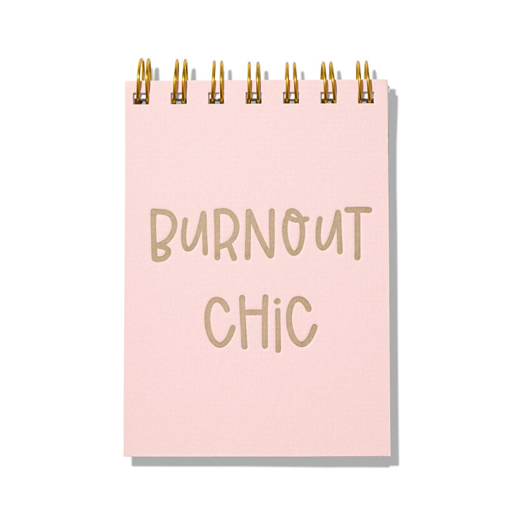 Pink letterpress mini jotter with gold text “Burnout Chic” and gold spiral binding.