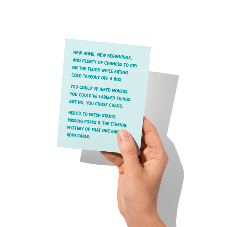 Funny new home card held in hand, humorous moving day humor visible.