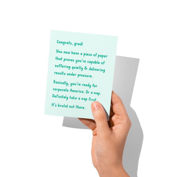 Funny graduation card held in hand, humorous congrats message visible.