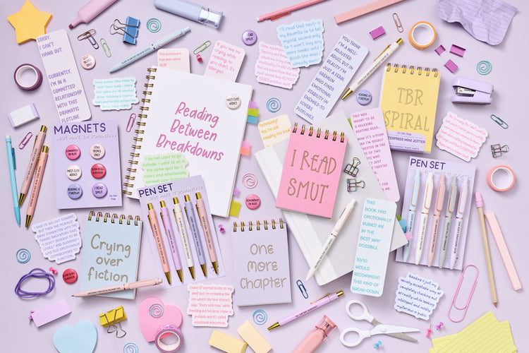 Assorted stationery items including notebooks, pens, and magnets on a light purple background