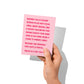 Funny holiday card held in hand, humorous Christmas message visible.