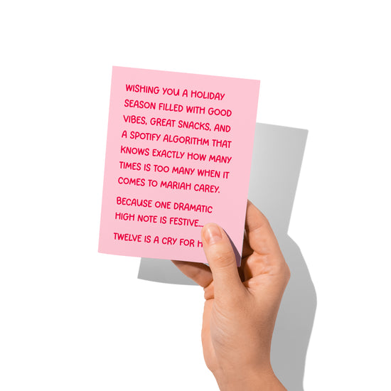 Funny holiday card held in hand, humorous Christmas message visible.