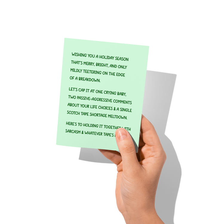 	Funny holiday card held in hand, humorous holiday chaos message visible.