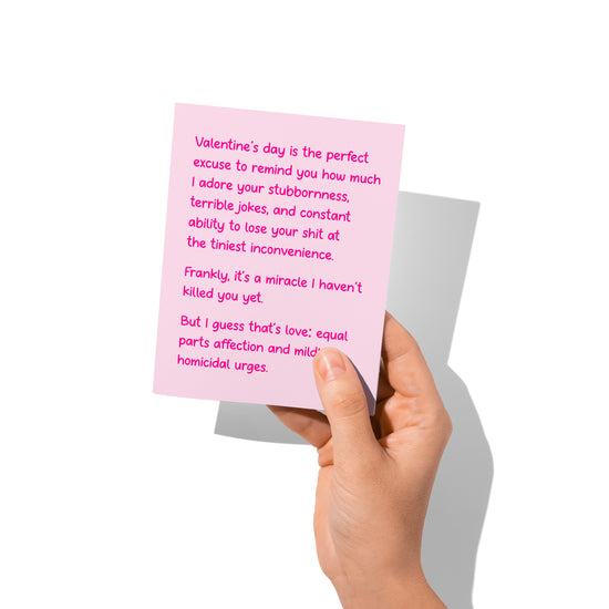 Funny Valentine’s card held in hand, humorous dark-affection message visible.