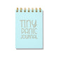 Light blue letterpress mini jotter with silver text “Tiny Panic Journal” and gold spiral binding.
