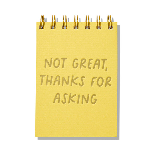 Yellow letterpress mini jotter with gold text “Not Great, Thanks for Asking” and spiral binding.
