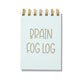 Blue letterpress mini jotter with gold text “Brain Fog Log” and spiral binding.
