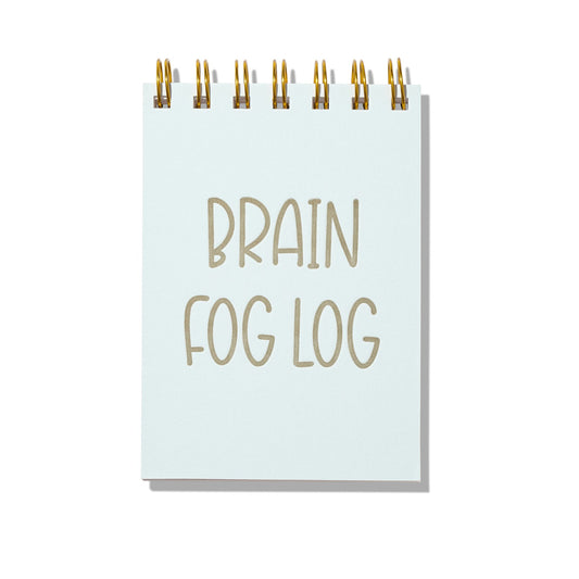 Blue letterpress mini jotter with gold text “Brain Fog Log” and spiral binding.
