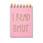 Pink mini jotter with letterpress text “I Read Smut” and gold spiral binding.