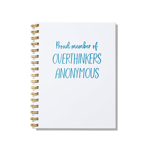 Large letterpress notebook with “Proud Member of Overthinkers Anonymous” in blue text on a white cover with gold spiral binding.
