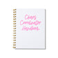 Large letterpress notebook with “Chaos Coordinator Handbook” in pink text on white cover with gold spiral binding.
