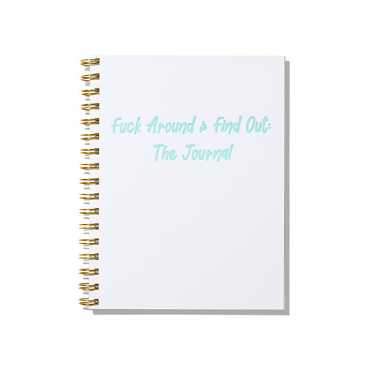 Large letterpress notebook with “Fuck Around & Find Out: The Journal” in aqua-blue text on white cover with gold spiral binding.
