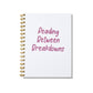Large letterpress notebook with magenta text “Reading Between Breakdowns” on white cover with gold spiral binding.