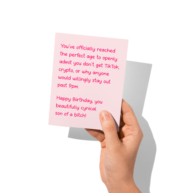Funny birthday card held in hand, humorous cynical design.