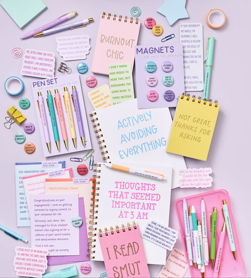 Collection of stationery items including notebooks, pens, and post-it notes on a light purple background