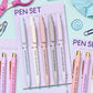 Set of pens with unique phrases on a purple card, surrounded by stationery items.